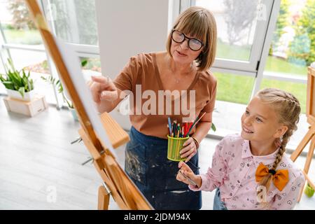 Enseignante mature parlant avec son élève pendant la classe à l'intérieur de l'école d'art Banque D'Images