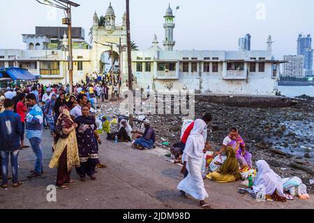 Mumbai, Maharashtra, Inde : les pèlerins marchent au-delà des mendiants sur la chaussée menant au 19ème siècle Haji Ali Dargah et la mosquée qui contient le tombeau Banque D'Images