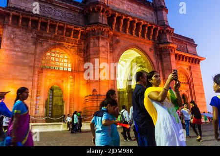 Mumbai, Maharashtra, Inde : les gens posent pour les selfies au crépuscule devant la porte illuminée de l'Inde arche monumentale construite entre 1913 et 1924 i Banque D'Images