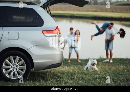 TERNOPIL, Ukraine - 12 septembre 2021: Sienna gris Toyota avec le tronc ouvert et flou heureux quatre membres famille avec chien d'animal de compagnie ayant le temps d'amusement Banque D'Images