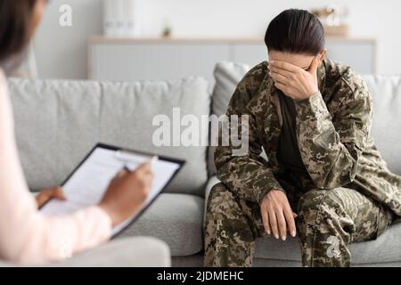 Psychothérapie avec les anciens combattants. Soldat féminin déprimé ayant une réunion de counseling avec un psychiatre Banque D'Images