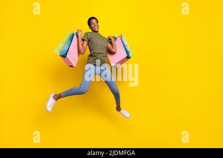 Portrait complet de la personne folle excitée saut tenir des paquets isolés sur fond jaune couleur Banque D'Images