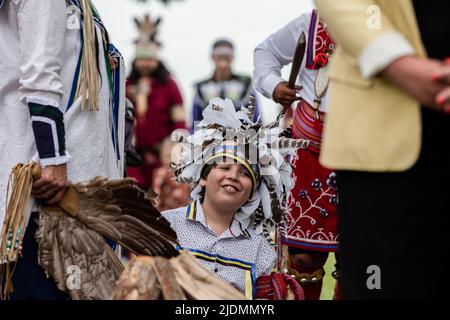 Montréal, Canada. 21st juin 2022. Un enfant indigène entouré par leur famille lors de la célébration du solstice d'été. Au cours de ce solstice d'été, les Canadiens ont célébré la Journée nationale des peuples autochtones de 26th. De nombreux membres des Premières nations de l'île Turtle (Montréal), de Kahnawake et d'ailleurs, ont dansé et partagé leurs histoires au cours de la transition saisonnière dans plusieurs événements à travers la ville. Parlant à Kanien'kehá avant le français ou l'anglais, les autochtones ont mis en valeur leur culture et leurs traditions dans le Vieux-Montréal. Crédit : SOPA Images Limited/Alamy Live News Banque D'Images