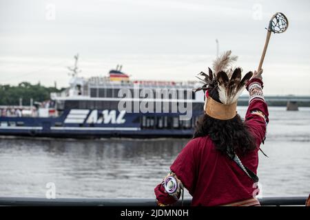 Montréal, Canada. 21st juin 2022. Une danseuse indigène agitant à un navire qui passe sur le fleuve Saint-Laurent pendant les célébrations du solstice d'été. Au cours de ce solstice d'été, les Canadiens ont célébré la Journée nationale des peuples autochtones de 26th. De nombreux membres des Premières nations de l'île Turtle (Montréal), de Kahnawake et d'ailleurs, ont dansé et partagé leurs histoires au cours de la transition saisonnière dans plusieurs événements à travers la ville. Parlant à Kanien'kehá avant le français ou l'anglais, les autochtones ont mis en valeur leur culture et leurs traditions dans le Vieux-Montréal. Crédit : SOPA Images Limited/Alamy Live News Banque D'Images