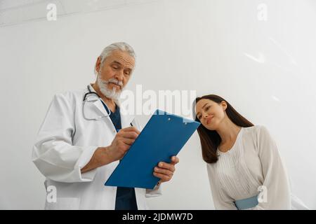 Le médecin remplit le formulaire de rapport médical sur les soins médicaux des patients pendant le rendez-vous Banque D'Images