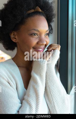 Jeune femme afro-américaine souriante qui regarde loin de chez elle Banque D'Images