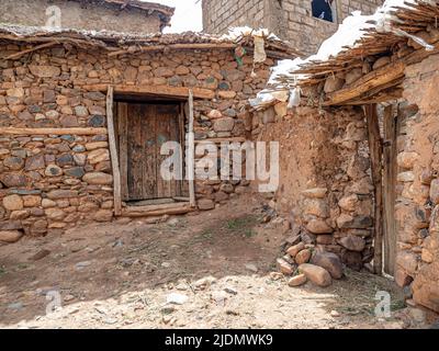 Village de la famille Berber avec murs en pierres et argile, et portes, toits et clôtures construits à partir de branches d'arbres. Montagnes de l'Atlas et ciel bleu en bac Banque D'Images