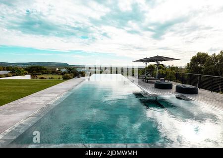 Vue panoramique du ciel nuageux se reflétant sur la piscine dans la cour de la maison de retraite Banque D'Images