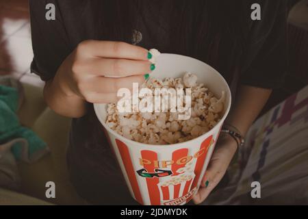 jeune femme mangeant du pop-corn dans un seau Banque D'Images