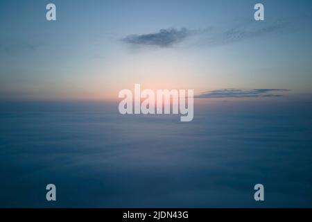 Vue aérienne d'en haut à haute altitude de nuages de cumulus bouffis denses volant en soirée. Coucher de soleil incroyable du point de vue de la fenêtre de l'avion Banque D'Images