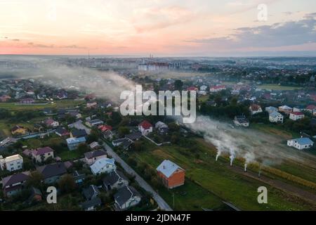 Vue aérienne des feux de déchets agricoles provenant de l'herbe sèche et de la paille brûlée avec de la fumée épaisse polluant l'air pendant la saison sèche sur les terres agricoles Banque D'Images