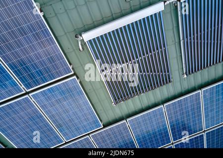 Toiture de bâtiment avec rangées de panneaux photovoltaïques bleus et capteurs solaires d'air sous vide pour le chauffage de l'eau et la production d'électricité écologique propre Banque D'Images