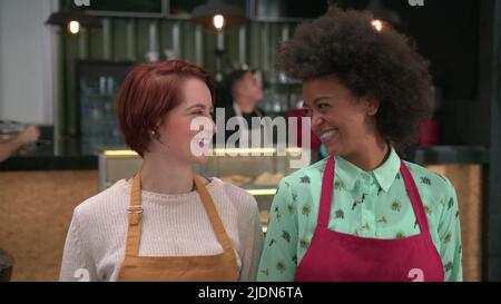 Portrait de deux femmes baristas dans des tabliers au café. Les jeunes employés de la cafétéria sont heureux les filles serveuses souriantes face au café Banque D'Images