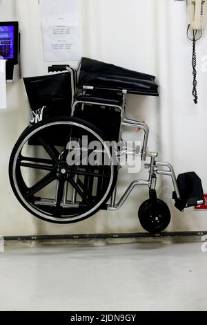 fauteuil roulant accroché au mur dans un espace équipiers pour une valise d'urgence et un extincteur à côté avec téléphone Banque D'Images