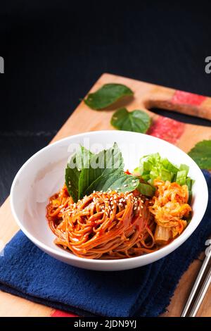 Food concept korean Spice Cold sarrasin Noodle Kimchi Bibim Guksu sur bois et fond noir avec espace de copie Banque D'Images