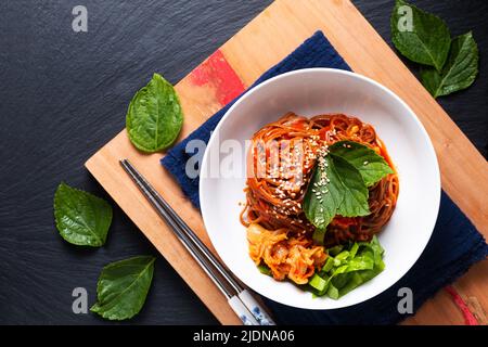 Food concept korean Spice Cold sarrasin Noodle Kimchi Bibim Guksu sur bois et fond noir avec espace de copie Banque D'Images