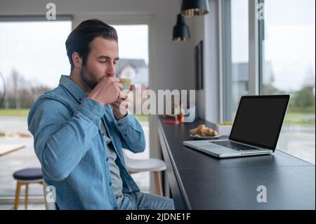 Homme buvant du café avec les yeux fermés assis dans le café Banque D'Images