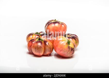 Plusieurs tomates de la variété du tigre sur fond blanc. Banque D'Images