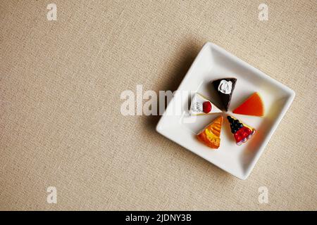 Modèle miniature de bonbons colorés alignés sur une assiette carrée blanche Banque D'Images