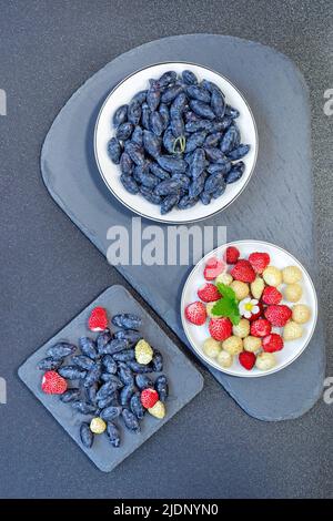 Les premières baies de la saison, le chèvrefeuille et les fraises sont sur la table. Mise au point sélective, vue de dessus Banque D'Images