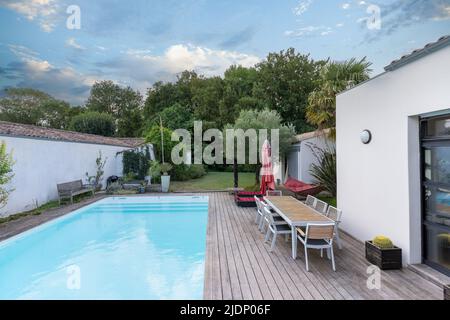 Maison moderne extérieure tendance, piscine, salon-jardin, chaises, grill en métal entouré d'un paysage Banque D'Images