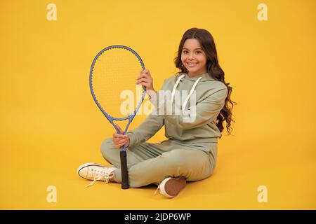 enfant dans les vêtements de sport tenir raquette. enfant avec raquette. jeune fille se détendre après l'entraînement sportif. Banque D'Images