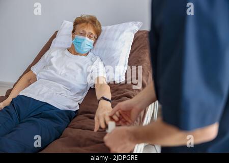 Vérification par le personnel infirmier de la saturation en oxygène du sang du patient à l'hôpital à l'aide de l'oxymètre de pouls Banque D'Images