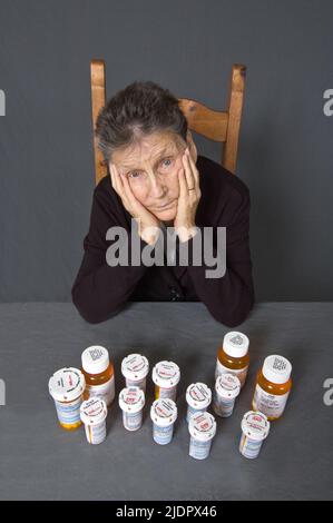 Une femme de 85 ans, latina assise devant tous les médicaments qu'elle prend pour ses diverses affections. Banque D'Images
