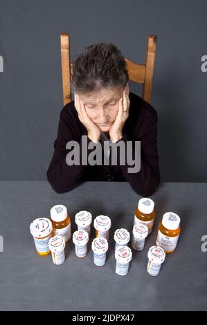 Une femme de 85 ans, latina assise devant tous les médicaments qu'elle prend pour ses diverses affections. Banque D'Images