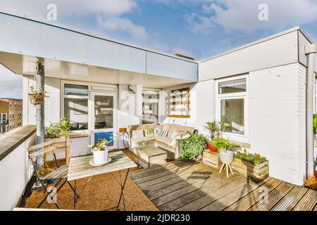 Espace détente avec canapé, table et chaises, plantes sur un grand balcon d'un bâtiment de plusieurs étages Banque D'Images