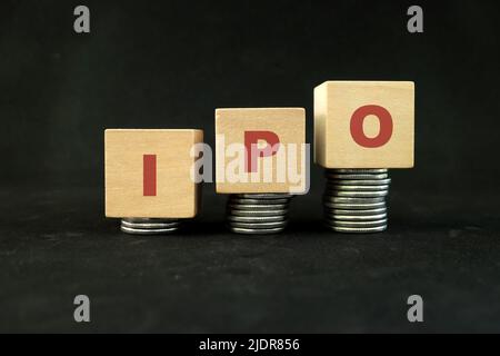 Concept initial de croissance de l'investissement sur le marché boursier. Les lettres IPO dans la pile croissante de pièces sur fond noir foncé. Banque D'Images