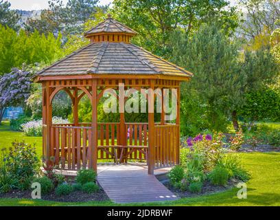 Pergola en bois dans un beau jardin vert. Photo de rue, personne, mise au point sélective. Magnifique belvédère Banque D'Images