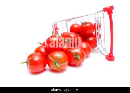 Chariot à jouets renversé avec tomates cocktail fraîches isolées sur blanc. Banque D'Images