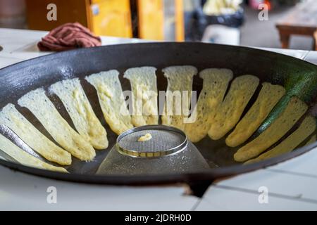 Un chef prépare des plats traditionnels du nord-est, des crêpes en bâton dans une poêle à repasser Banque D'Images