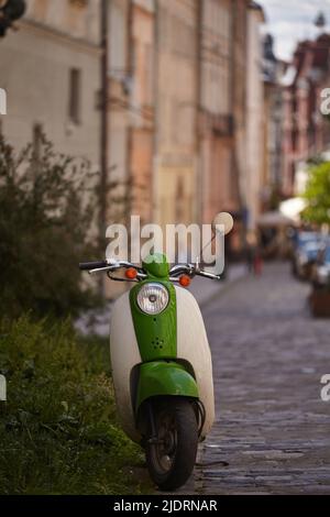 Trottinette rétro garée sur la rue de la ville. Scooter vert blanc debout sur un côté de la route Banque D'Images