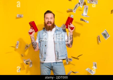 Photo de funky excitée Guy habillé gilet de denim tir argent volant air isolé couleur jaune arrière-plan Banque D'Images