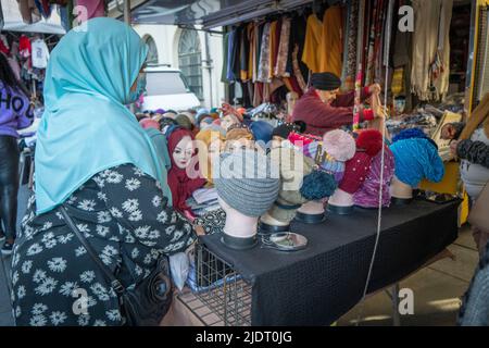 Une femme musulmane aide un client à trouver un foulard ou un hijab approprié à partir d'une série de mannequins sur un marché local à Turin, en Italie Banque D'Images