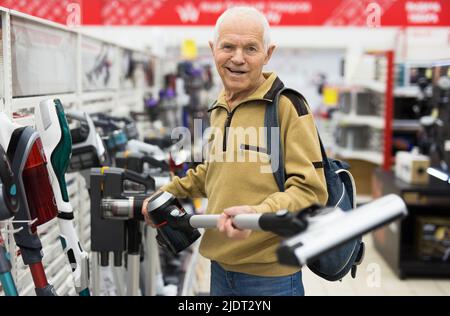 Sénior homme retraité achetant l'aspirateur vertical dans la salle d'exposition du magasin d'appareils électriques Banque D'Images