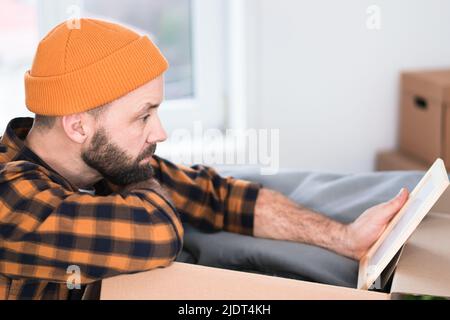 Hipster homme avec des boîtes mobiles dans nouvel appartement moderne. Homme mûr déballant des objets des boîtes tout en déplaçant dans un nouvel appartement. Banque D'Images