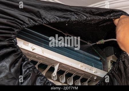 Le technicien nettoie le climatiseur en pulvérisant de l'eau et des produits chimiques. Faible profondeur de champ. Mise au point sélective Banque D'Images