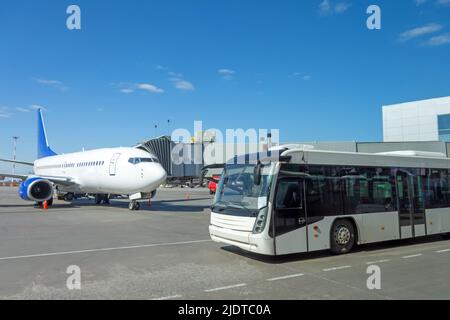 Autobus blanc pour transporter des passagers du terminal à la rampe d'embarquement de l'avion pendant la procédure de départ du vol Banque D'Images