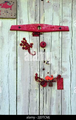 Vieille porte à ragoût décorée de métal Junk, y compris Toy Metal Lizard et Old Rake Head On Boat Shed on Bregancon Beach Var Provence France Banque D'Images