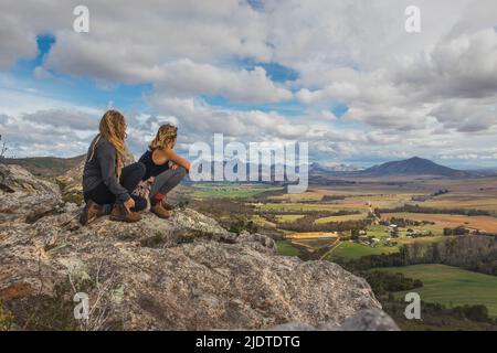 Deux filles sur une montagne qui donne sur les terres agricoles. Banque D'Images