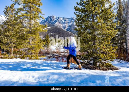 États-Unis, Idaho, Ketchum, femme blonde senior raquette dans un paysage enneigé Banque D'Images