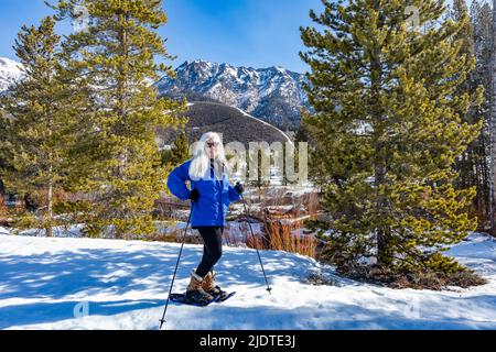 USA, Idaho, Ketchum, Portrait de femme blonde senior souriante avec raquettes dans le paysage Banque D'Images