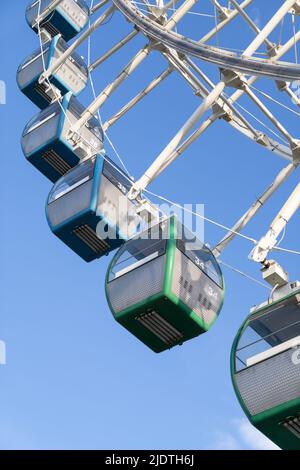 Gros plan de cabines colorées de la grande roue de ferris dans le parc d'attractions contre le ciel bleu Banque D'Images
