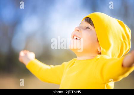 Portrait de l'enfant heureux sur fond de feuilles jaunes. Enfant souriant s'amuser en plein air dans le parc d'automne. Concept de liberté et d'imagination Banque D'Images