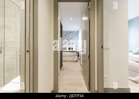 Distributeur d'une maison avec accès à plusieurs chambres avec menuiserie en bois gris et une salle de bains avec cloison en verre Banque D'Images