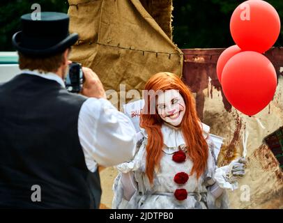 Pattensen, Allemagne, 4 juin 2022: Une jeune femme aux ballons rouges et vêtue comme un clown maléfique est accroché par un photographe lors d'un festival de fantaisie à Banque D'Images