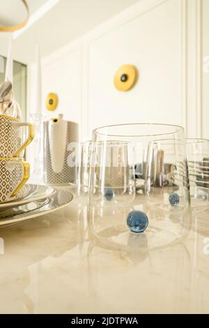 Image détaillée d'une grande table en marbre blanc avec assiettes, vaisselle en porcelaine, vases en verre et couverts en métal Banque D'Images